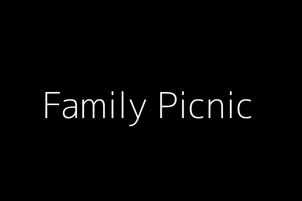 A family sitting in a circle on a park blanket, eating sandwiches and talking, with trees and sunlight around them.