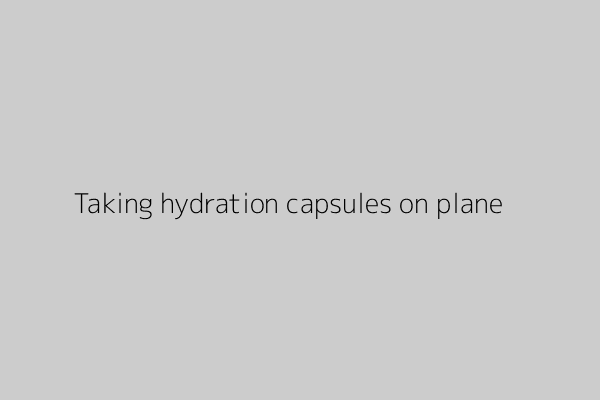 Person taking hydration capsules with a glass of water while seated on an airplane.